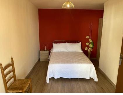 1 dormitorio con cama blanca y pared roja en Casa Tijeras I, en Sotillo de las Palomas