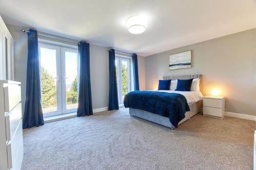 a bedroom with blue curtains and a bed and a window at Host & Stay - Castle View in Seahouses