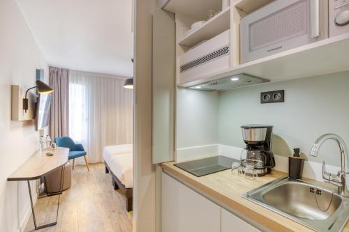 a kitchen with a sink and a room with a bed at Appart'City Confort Paris Clichy - Mairie in Clichy