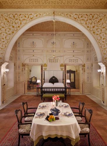a dining room with a table and a bed at The Laxmi Niwas Palace in Bikaner