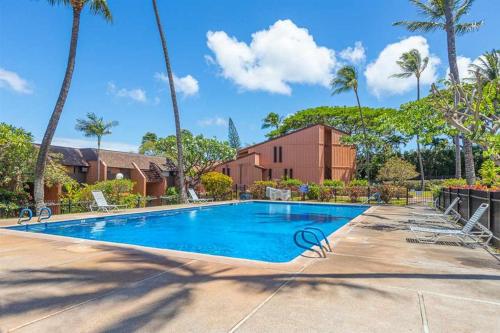 a swimming pool at a resort with palm trees at Kuleana Resort 209 in Kahana