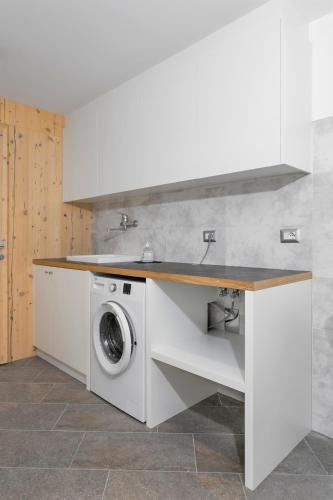a kitchen with a washing machine under a counter at Bellavista - Lake in Molveno