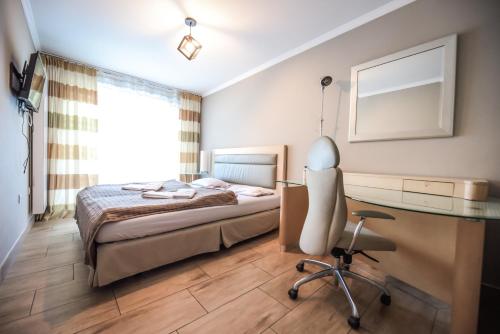 a bedroom with a bed and a desk and a chair at Aparthotel WADOWICE & Hostel GENERY in Wadowice