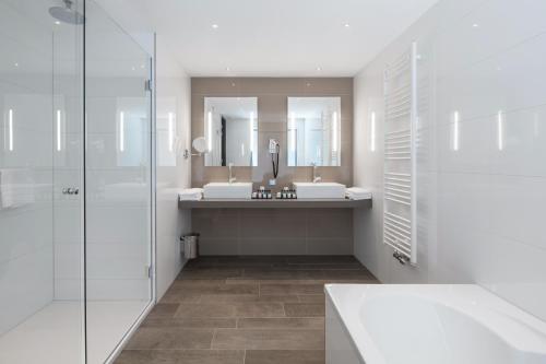 a bathroom with two sinks and two mirrors at Van der Valk Hotel Haarlem in Haarlem