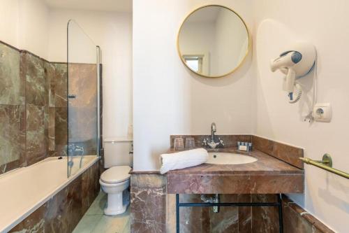 a bathroom with a sink and a toilet and a mirror at Catedral Suites Jerez in Jerez de la Frontera