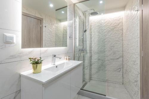 a white bathroom with a sink and a shower at Olea Apartment in Corfu Town