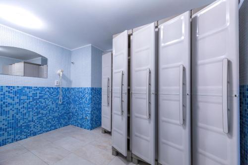 a bathroom with a row of white stalls and blue tiles at WX Hotel in Bratislava
