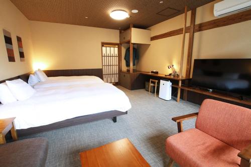a hotel room with a bed and a tv and a couch at Kutsurogijuku Chiyotaki in Aizuwakamatsu