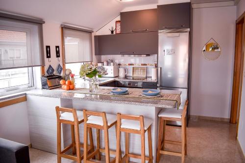 a kitchen with a counter with chairs and a refrigerator at La Xouba in Rianjo