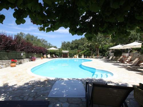 a large swimming pool in a yard with chairs at Andrikos studio A in (( Kalodhikátika ))