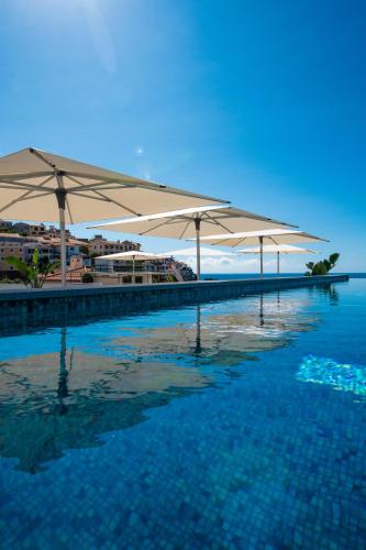 a pool of water with umbrellas on top of it at Pestana Fisherman Village in Câmara de Lobos