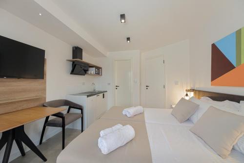 a bedroom with a white bed with a desk and a kitchen at 9 apartments in Jagodina
