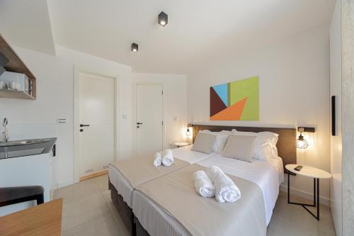 a bedroom with a large white bed with towels on it at 9 apartments in Jagodina