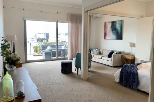 a bedroom with a bed and a living room with a couch at Mariner's Cove ~ Luxe Waterfront Apartment in Mindarie