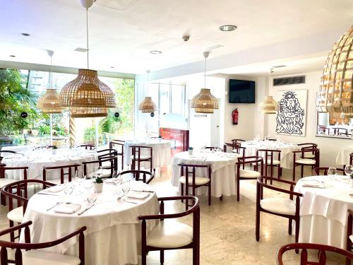 a dining room with white tables and chairs at Hotel Calasanz in Molins de Rei