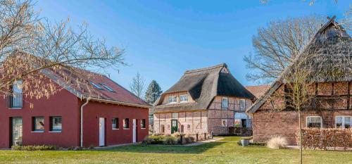 a group of three houses with a red building at HofGut Bockelkathen Apartment 3 in Lüdersburg