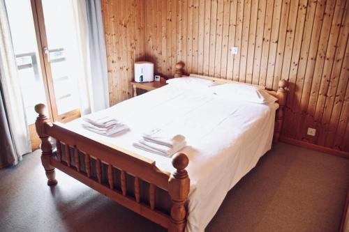 a bedroom with a bed with white sheets and a window at Chalet Le Jeuna in Morgins