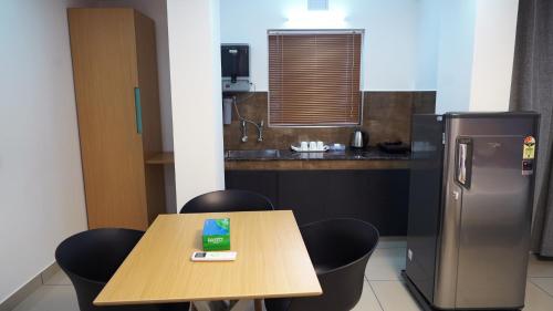 a small kitchen with a table and a refrigerator at The White Orchid Luxury Service Apartments in Ernakulam