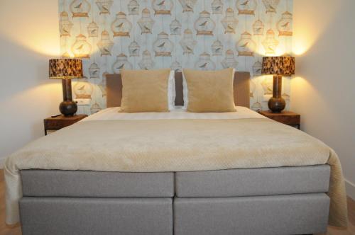 a bedroom with a large bed with two lamps at Hotel Abdijhof Thorn in Thorn