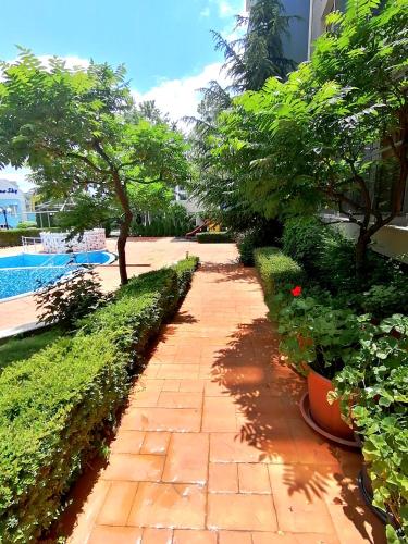 a brick walkway with trees and plants next to a pool at Sineva Del Sol Apartments in Sveti Vlas