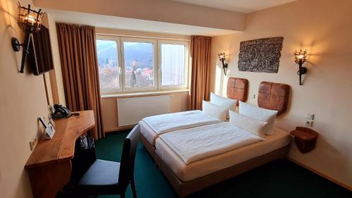 a bedroom with a bed and a desk and a window at Hasseröder Burghotel in Wernigerode