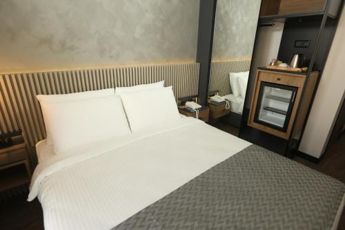 1 dormitorio con 1 cama grande con sábanas blancas en Moja City Hotel, en Estambul