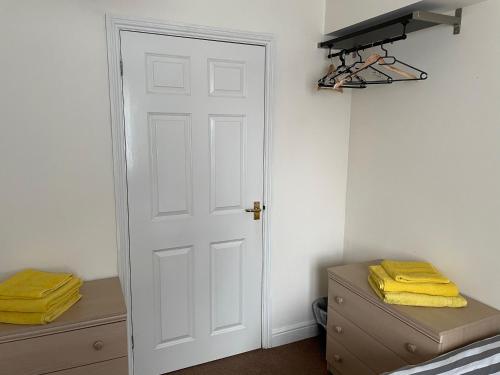 a white door in a bedroom with yellow towels at Entire 2 Bedroom Apartment free parking in Saffron Walden