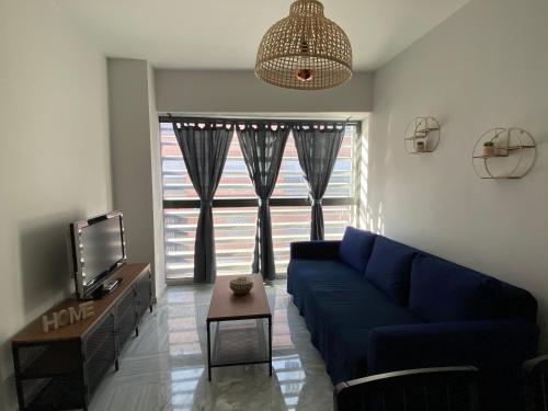 a living room with a blue couch and a tv at Quattro Triana en Salado in Seville