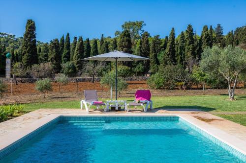 a swimming pool with two chairs and an umbrella at Ca Sa Padrineta in Capdepera