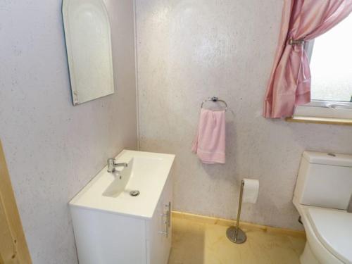 W łazience znajduje się umywalka, toaleta i różowy ręcznik. w obiekcie The Beautiful Lazy Llama Shepherd Hut Farm Stay w mieście Ballyshannon