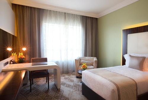 a hotel room with two beds and two lamps at Elite Byblos Hotel in Dubai