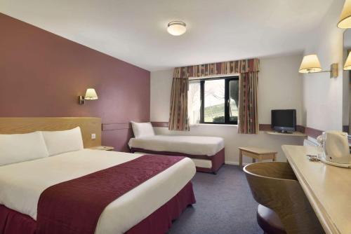 Days Inn Hotel Membury في Lambourn: غرفة في الفندق بها سرير وأريكة ومكتب