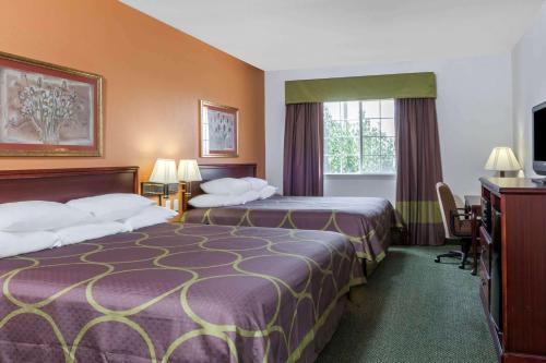 a hotel room with two beds and a desk at Super 8 by Wyndham Hillsboro TX in Hillsboro