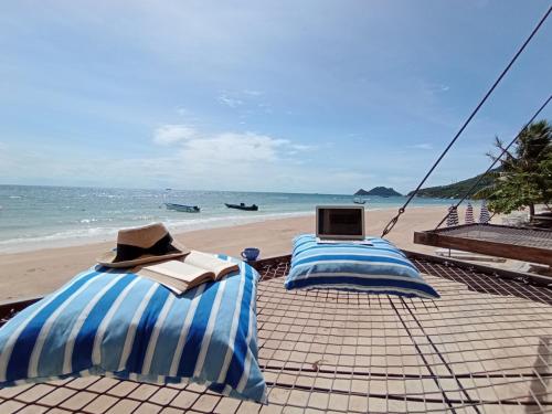 a beach with two umbrellas and a laptop on a beach at Blue Tao Beach Hotel - SHA Plus in Koh Tao