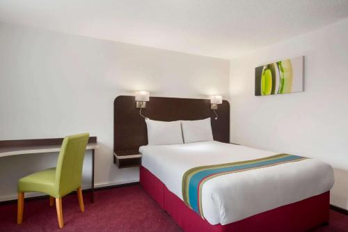 Habitación de hotel con cama y silla verde en Ramada London South Mimms, en Potters Bar