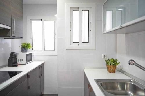 a white kitchen with a sink and two windows at SAGRADA FAMILIA VIEWS Nos preocupa su seguridad in Barcelona