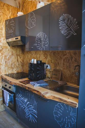 - une cuisine avec des placards bleus et blancs et une cuisinière dans l'établissement La Kanopée - Les Loges Normandes, à Cherbourg en Cotentin