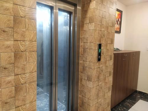 a glass elevator in a room with a stone wall at Hotel Geeta Residency Haridwar in Haridwār