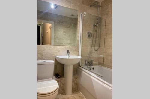 a bathroom with a sink and a toilet and a shower at Kensington Apartments in London