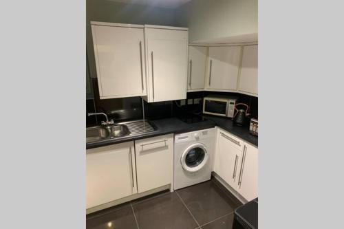 a kitchen with white cabinets and a washing machine at Kensington Apartments in London
