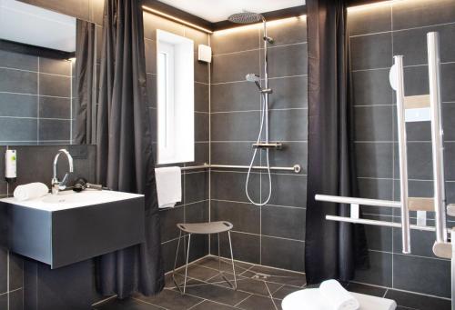 a bathroom with a sink and a shower at RHE Hotel by WMM Hotels in Rheinau