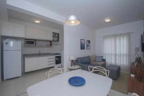 eine Küche und ein Wohnzimmer mit einem Tisch und einem Sofa in der Unterkunft Residencial Anchieta Riviera By Audaar in Riviera de São Lourenço