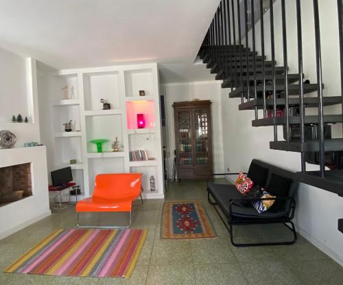 ein Wohnzimmer mit einer Treppe und einem orangenen Stuhl in der Unterkunft La casetta in Rocca San Felice