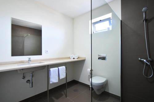 a bathroom with a sink and a toilet and a mirror at Surfivor Surf Camp in Esmoriz