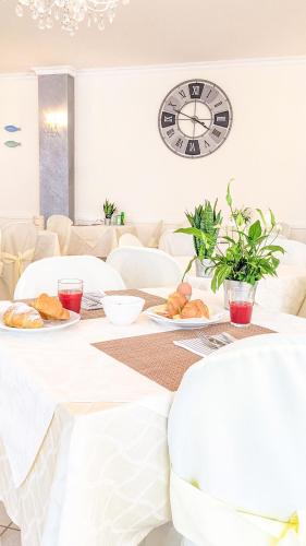 une table avec des assiettes de nourriture et une horloge sur le mur dans l'établissement Hotel Explorer, à Cervia