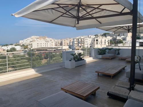 a rooftop patio with benches and an umbrella at Hotel Monte Sarago in Ostuni