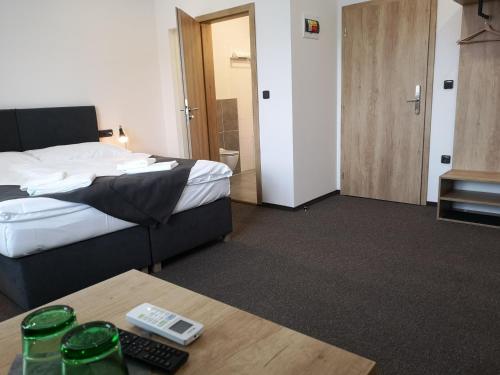 a hotel room with a bed and a table with a remote control at Penzion DON in Třebíč