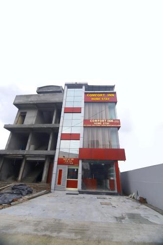 a tall building with a red and white at Hotel Comfort Inn Homestay in Dehradun