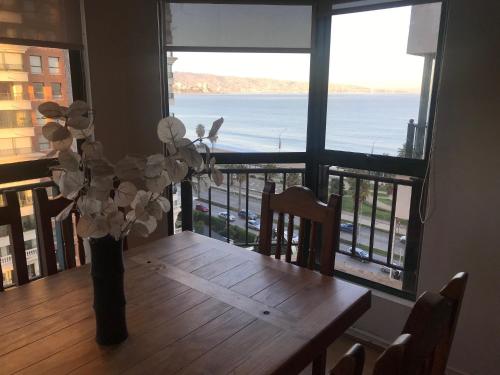 a dining room table with a vase with flowers on it at Departamento en Condominio Puerto Pacífico in Viña del Mar