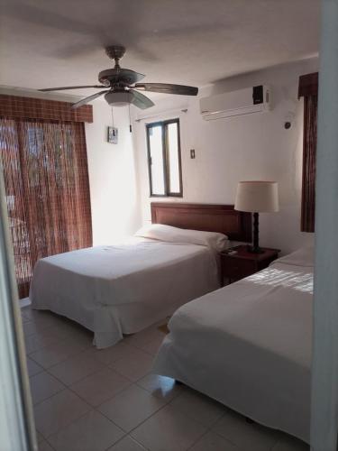 1 dormitorio con 2 camas y ventilador de techo en Corazón del Pescador, en Cancún